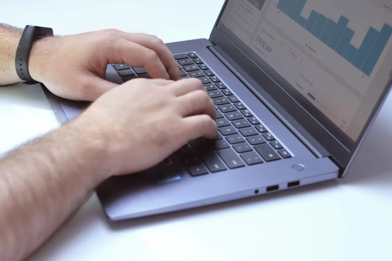 Hands working on a laptop with data analysis charts