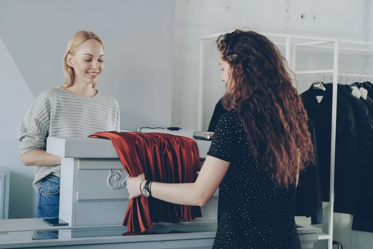 A retail assistant helping a customer at a clothing-store counter